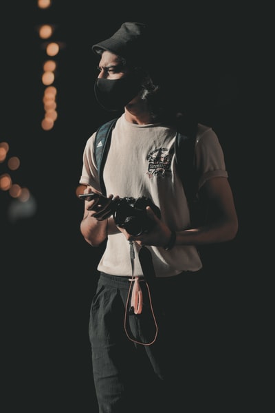 man in white tank top holding black dslr camera